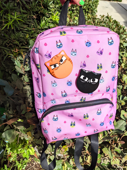 Two kawaii cat ear shaped buttons on a pink backpack.