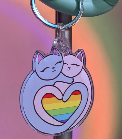 Keychain has two cats forming a heart with their tales. Within the heart is a rainbow pride flag Rainbow Heart Pride Flag Cats 