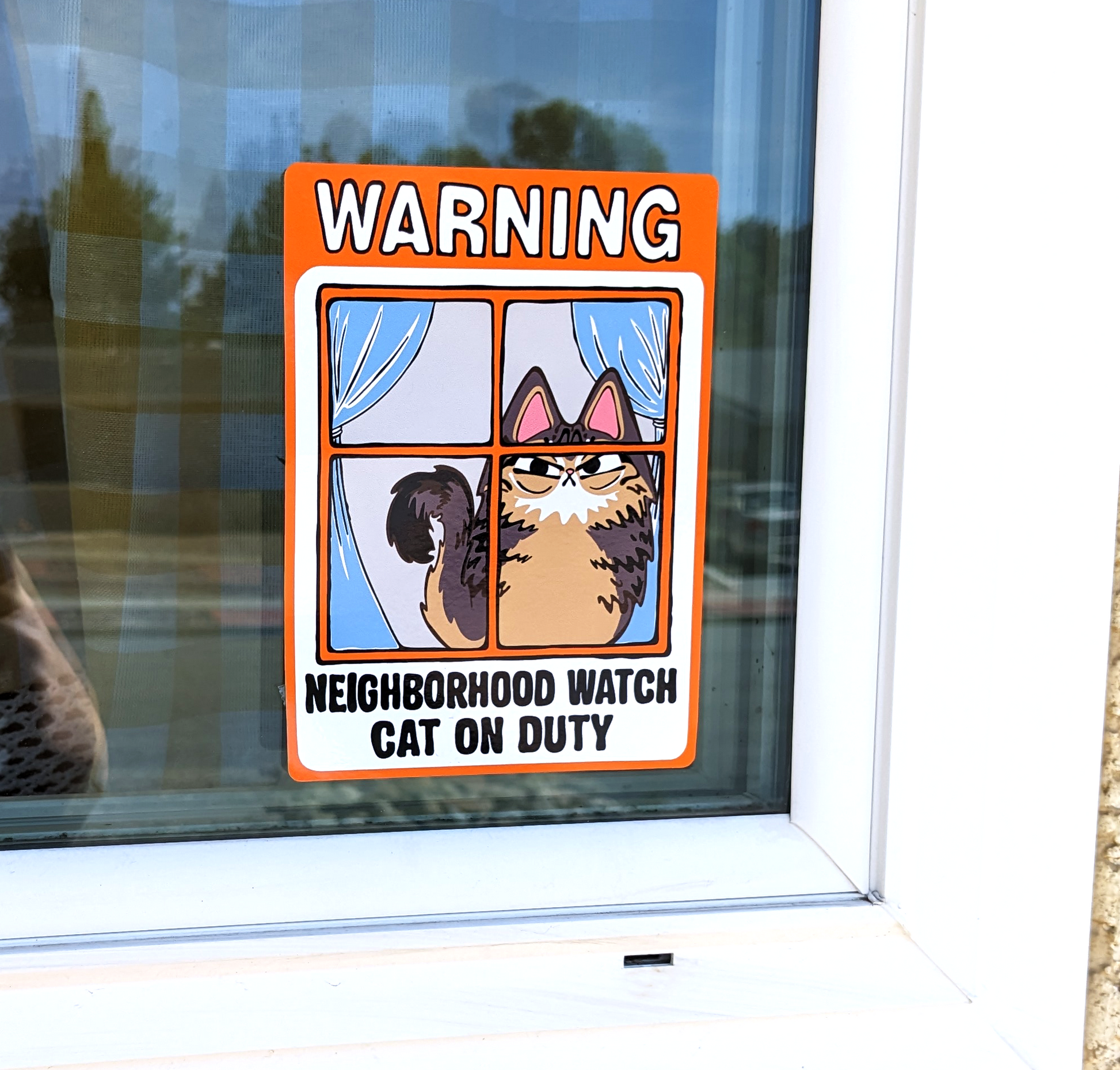 Angry Fluffy Tabby Cat Neighborhood Watch Cat Window Cling that reads Warning Neighborhood watch cat on duty is displayed on window outside