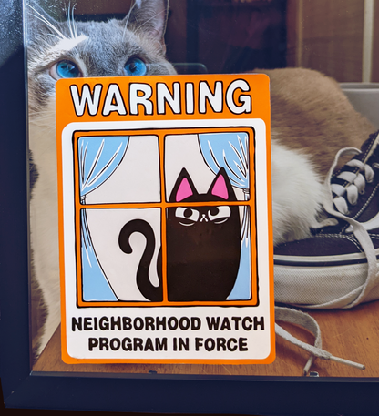 Neighborhood Watch Cat sign with judgy black cat stuck to window. Cute cat is behind static cling