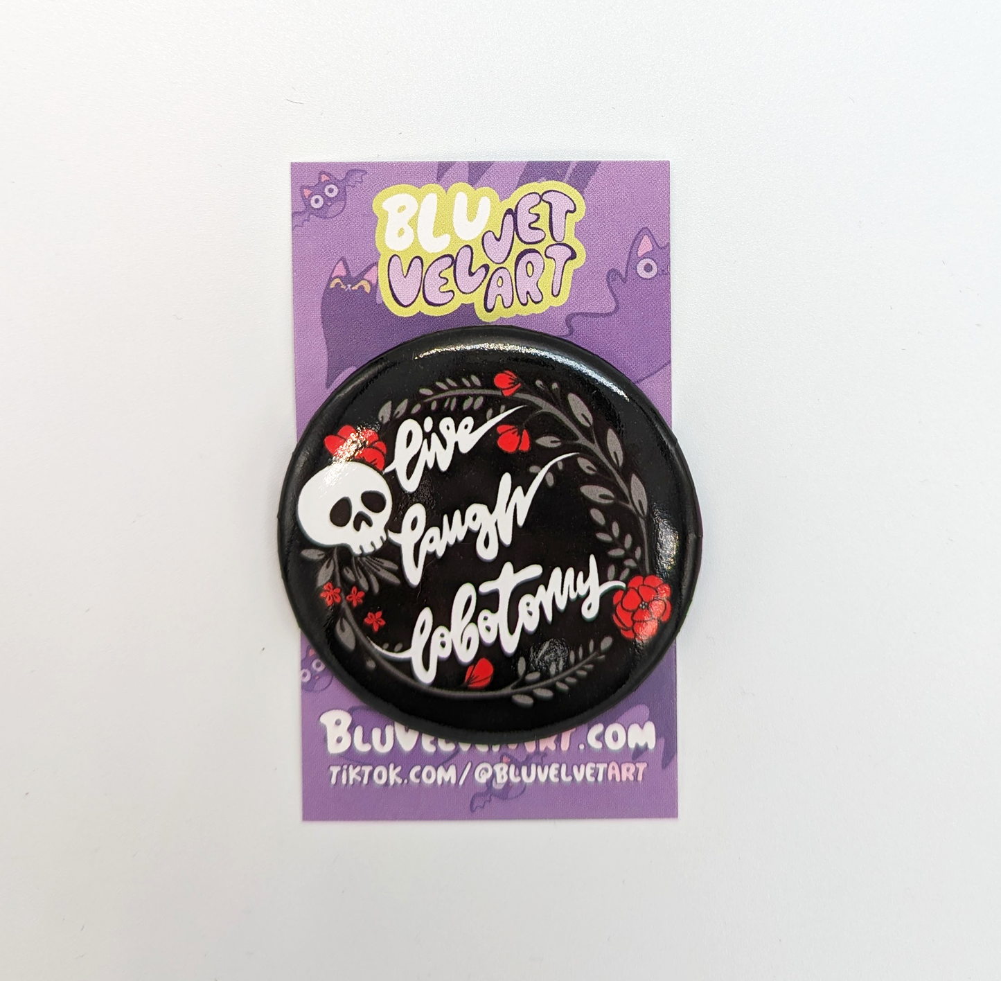 Live Laugh Lobotomy Button - Cute Memento Mori Design with Skull and Roses displayed on Bluvelvet Art backing card