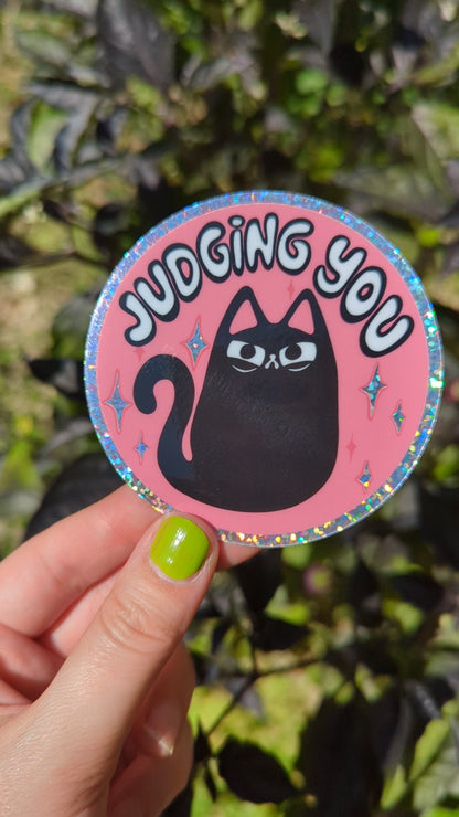 Glitter sticker of judgy angry black cat shines in the sun, each movements sparkles